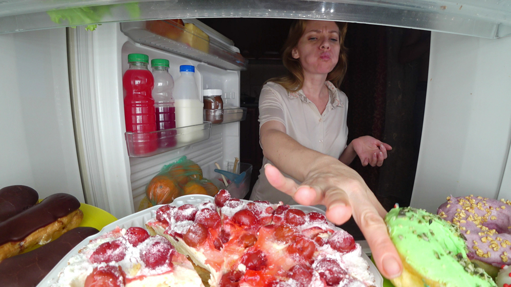 Woman opens the refrigerator at night. night hunger. diet gluttony