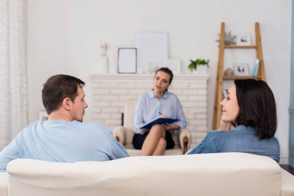 couple sitting on a couch talking while a third person takes notes