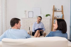 couple sitting on a couch talking while a third person takes notes