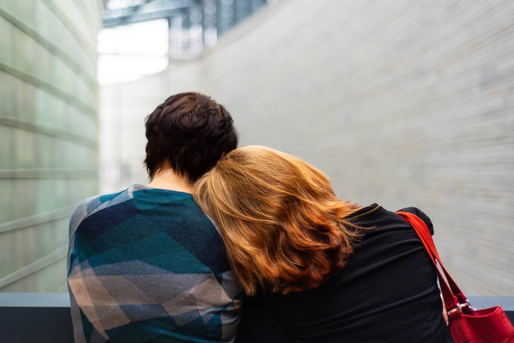 a couple with one person putting their head on the others shoulders